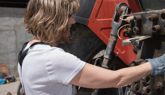 Woman mechanic repairing a tractor outdoors by Joe_McUbed (Canva)