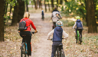 parents and kids cycling on forest trail by Yelizaveta