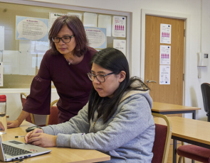 Two women in educational setting looking at a computer screen