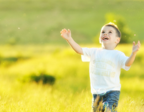 Boy chasing bubbles in field