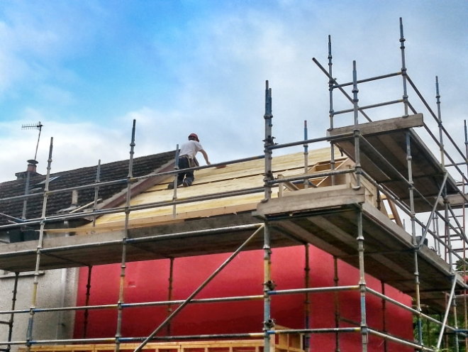 Construction worker on scaffold during house build 