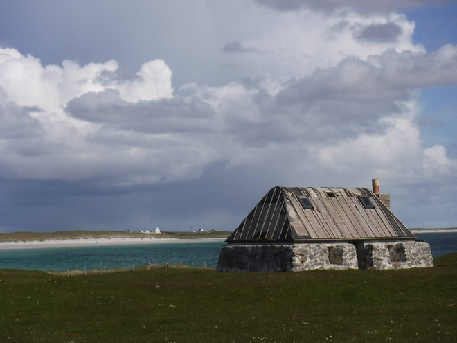 Old stone black house set above sea and beach