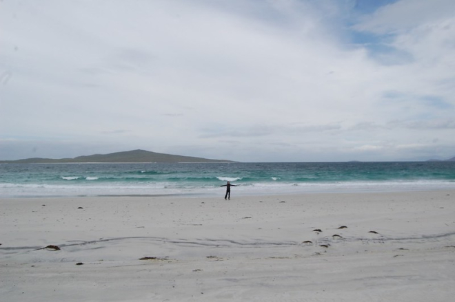 Small figure with arms wide on huge white beach