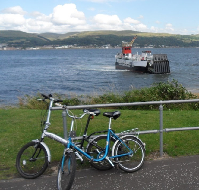 Two bikes leaning against railing with ferry in background