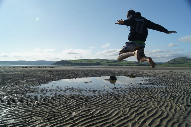 Boy jumping over seawater pool on beach 