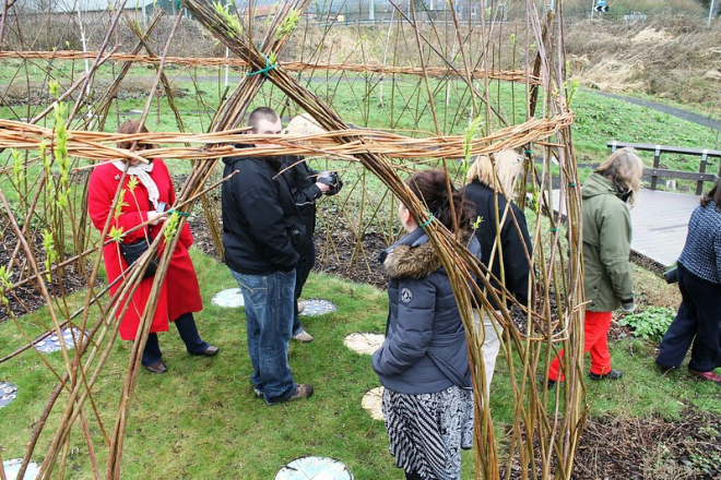 Group of people in garden with woven willow fencing