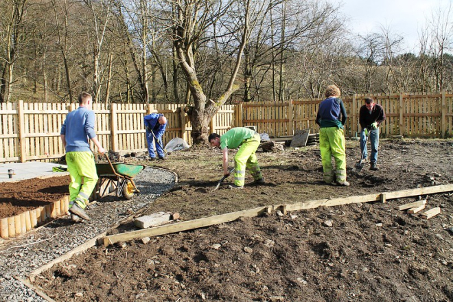 Four men with spades, one pushing a wheelbarrow creating paths