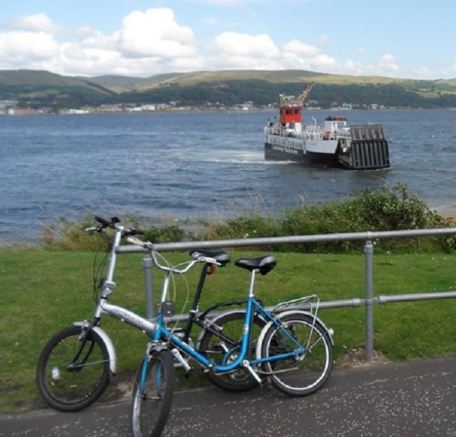 Two bikes  propped against a railing with a ferry in the background