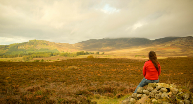 Girl sitting on rock looking at landscape