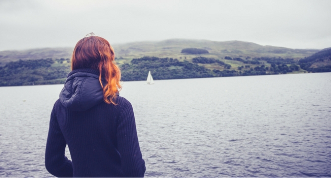 Woman standing at side of loch