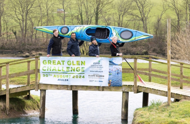 Alasdair Forsyth, Solicitor in Land and Rural Business at Gillespie Macandrew, Harry Seran, Head of Finance and Compliance at RSABI, Carol McLaren, RSABI Chief Executive and Lois Newton, Partner of Land and Rural Business at Gillespie Macandrew holding a canoe while standing on a footbridge 