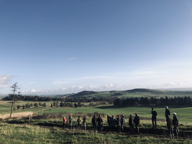 Group of people listening to speaker in rolling farmland