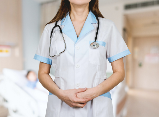 Doctor in white caot with blue trim. Stethoscope around her neck