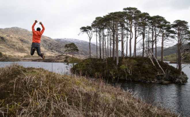 Person jumping at side of loch