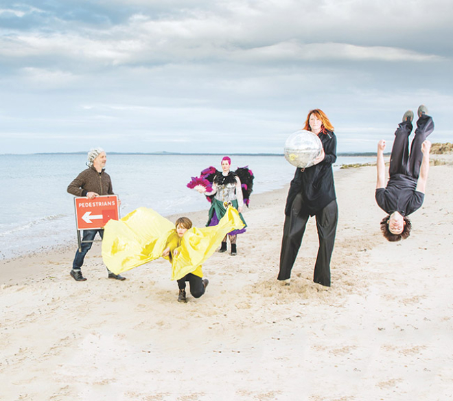 Five people dancing on a beach