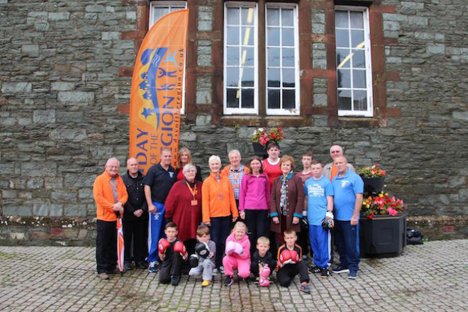 Group of people outside stone building with Day of the Region banner