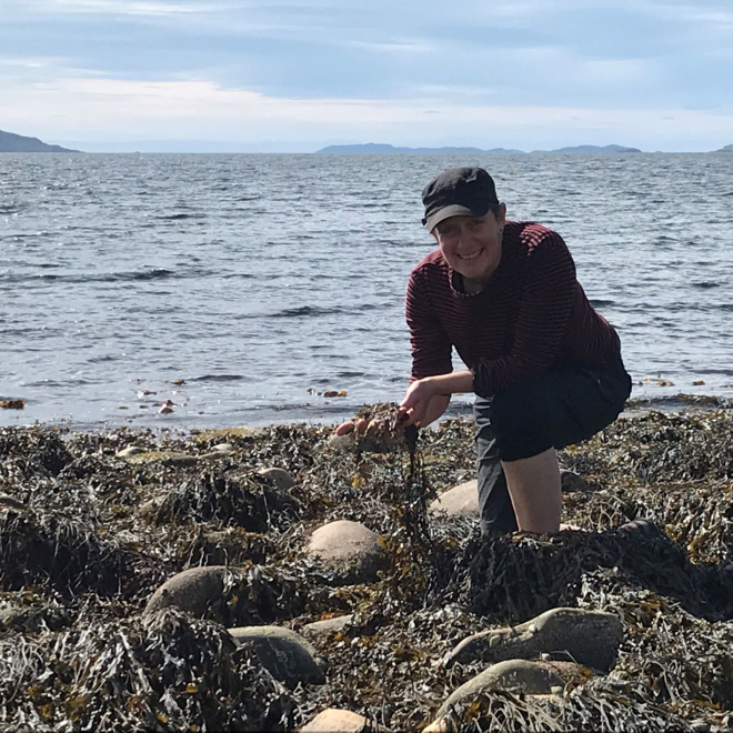 Woman kneeling on beach with seaweed