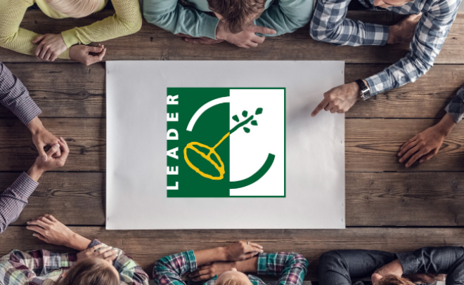 People sitting round table with LEADER logo on paper in the middle