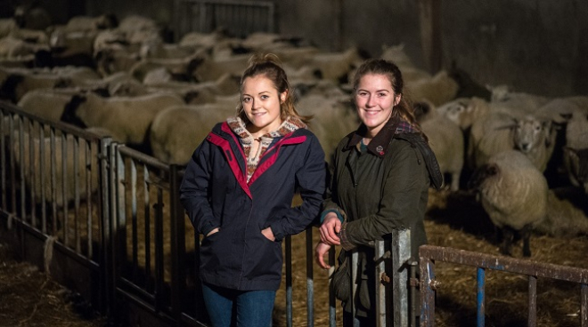 Sisters Kirsty and Aimee Budge standing in front of sheep