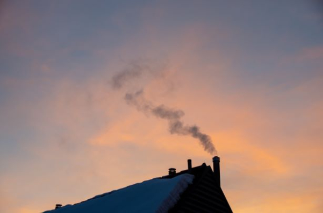 orange wintery sky with snow covered roof in foreground