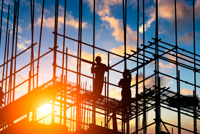 outline of construction workers on scafolding with sun behind them