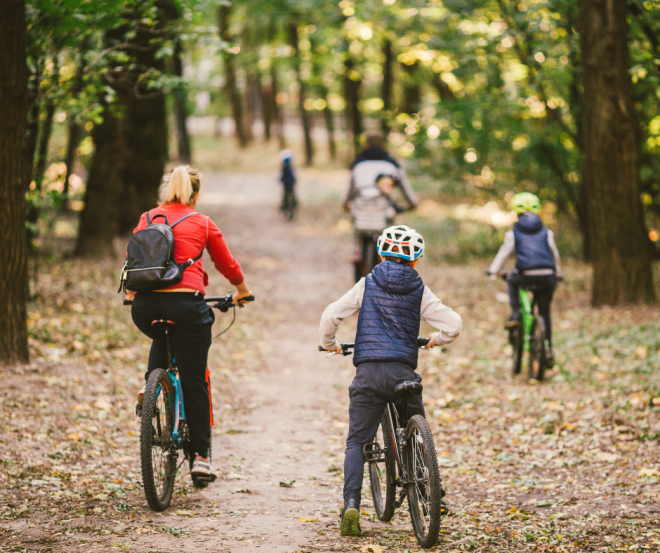 parents and kids cycling on forest trail by Yelizaveta