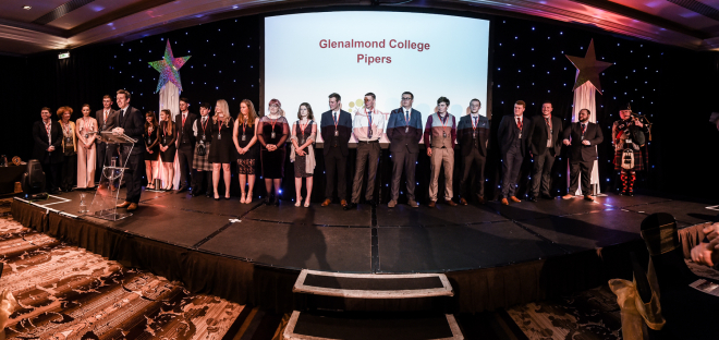 Group of 20 young people on stage behind compere