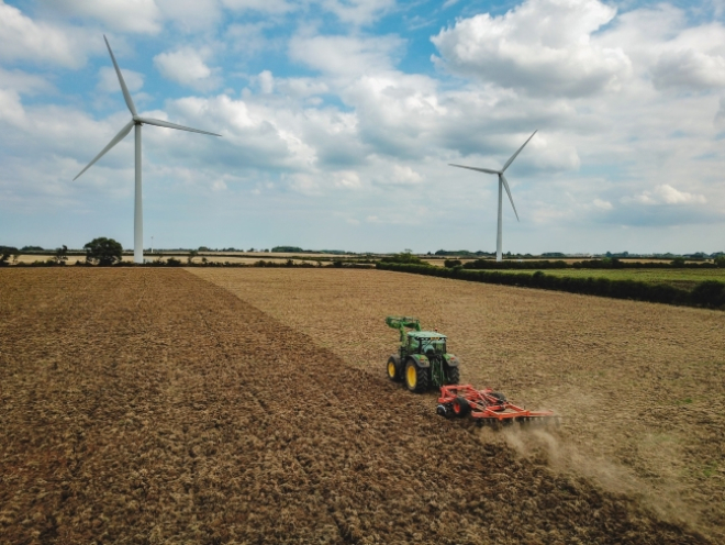 Tractor in field with wind turbines in the distance