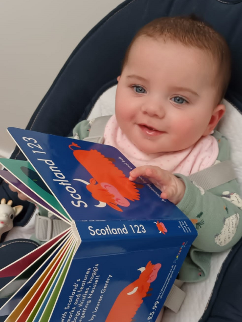 baby  in a highchair with a picture book