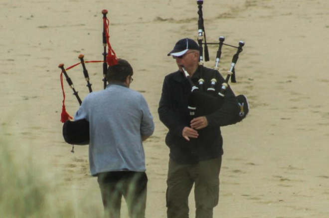 two men playing bagpipes on the beach