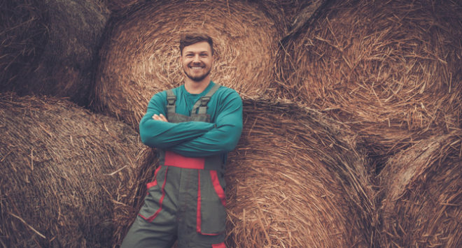 young farmer leaning against bales