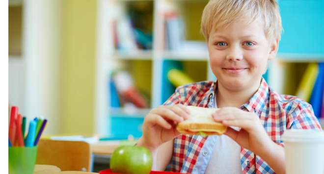 boy eating lunch at school desk