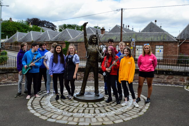 Young musicians from the DD8 project stand beside Kirriemuir Bon Scott statue