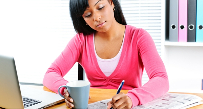 Woman sitting at computer looking at jobs in the paper