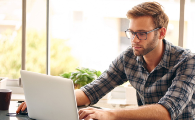 Man sitting at table looking at laptop