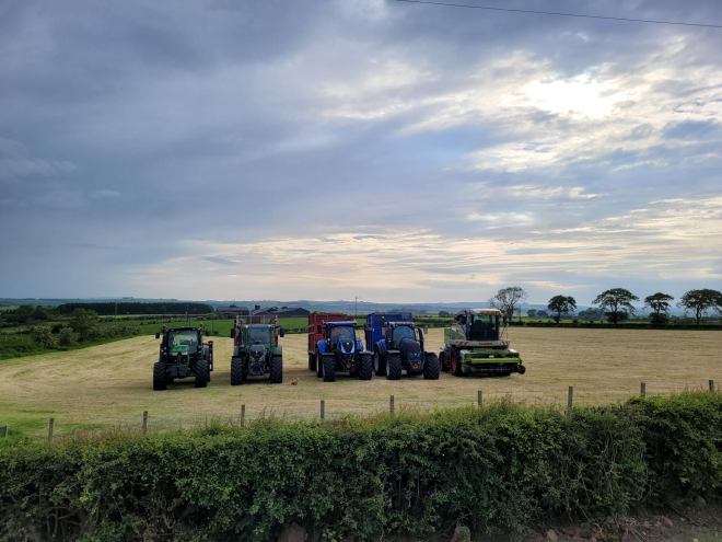 Four tractors and a chopper lined up in a freshly cut silage field